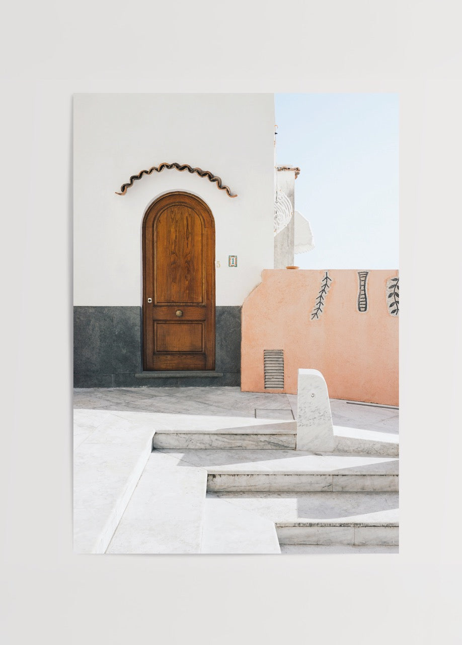Kavisli ahşap kapısı ve pastel tonlarda duvarları olan Akdeniz mimarisi detaylı minimal bir bina fotoğrafı.