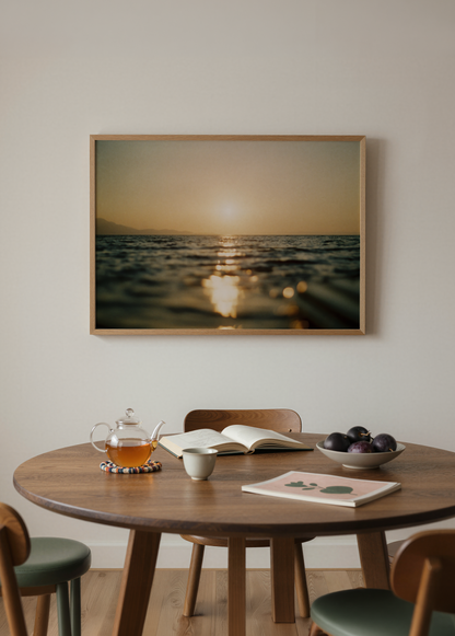 Deniz üzerinde gün batımının altın yansımalarını ve ufukta batan güneşi gösteren sıcak tonlu minimalist sahil fotoğrafı.