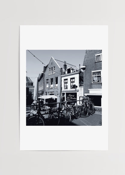 Merve Kurt’un Amsterdam’da çektiği siyah-beyaz fotoğraf, bisikletler ve tarihi kafe detaylarını ölümsüzleştiren poster baskı.