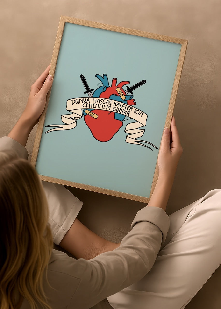 duygulariyerim’in “Dünya Hassas Kalpler İçin Cehennem Gibidir” posteri – açık mavi fonda kalp, bıçak ve yara bandı detaylı duygusal illüstrasyon