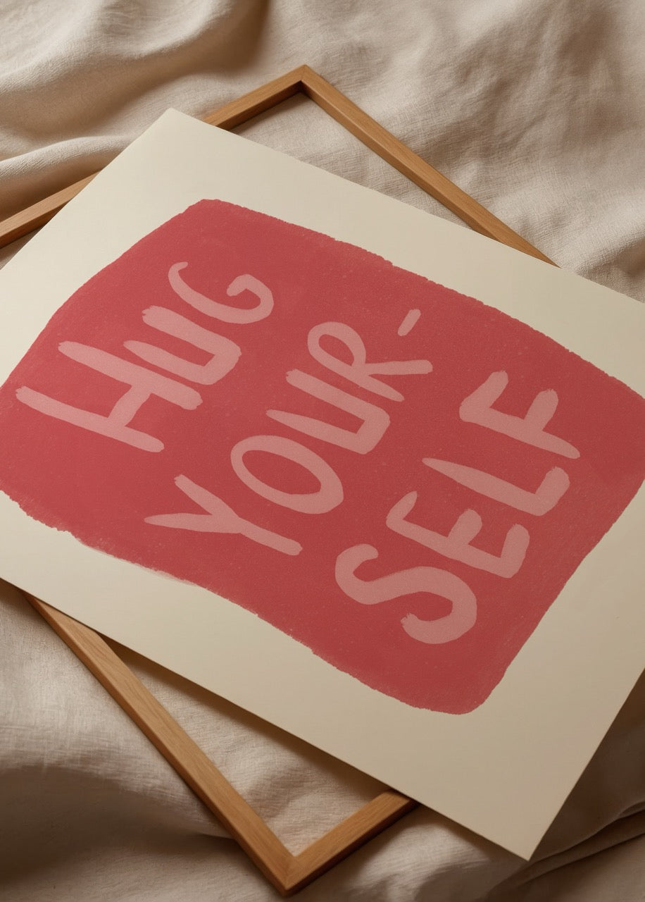 Krem zemin üzerinde, kırmızı bir formun içinde el yazısı karakterde “Hug Yourself” yazan sade ve duygusal illüstrasyon.
