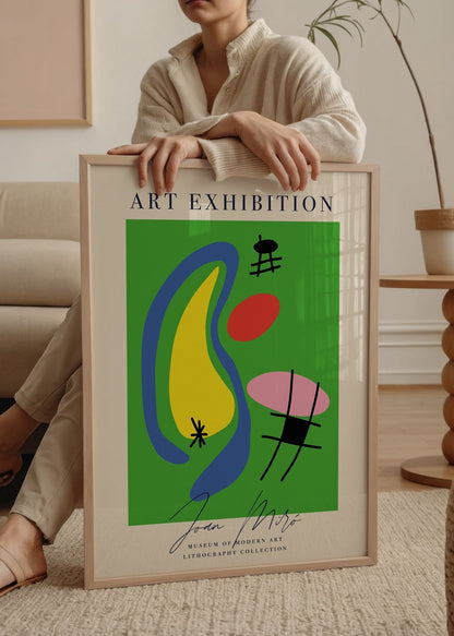 Yeşil zemin üzerinde sarı, mavi, kırmızı ve pembe şekillerin yer aldığı, Joan Miró imzalı modern litografi poster.