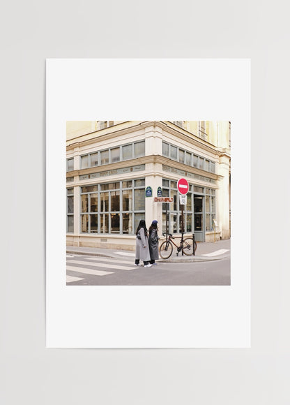 Merve Kurt tarafından çekilmiş pastel tonlu Paris sokak köşe fotoğrafı, bisiklet ve iki figür ile şehir dokusu.