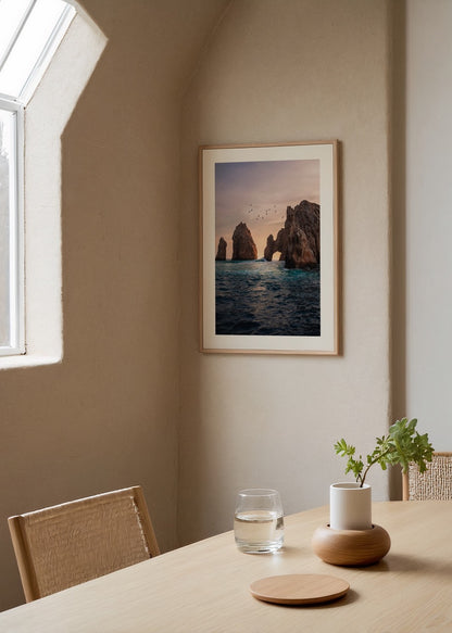 Gün batımında deniz üzerinde kaya kemerleri ve uçan kuşlar, doğa ve seyahat temalı poster.