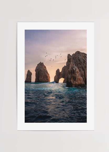 Gün batımında deniz üzerinde kaya kemerleri ve uçan kuşlar, doğa ve seyahat temalı poster.