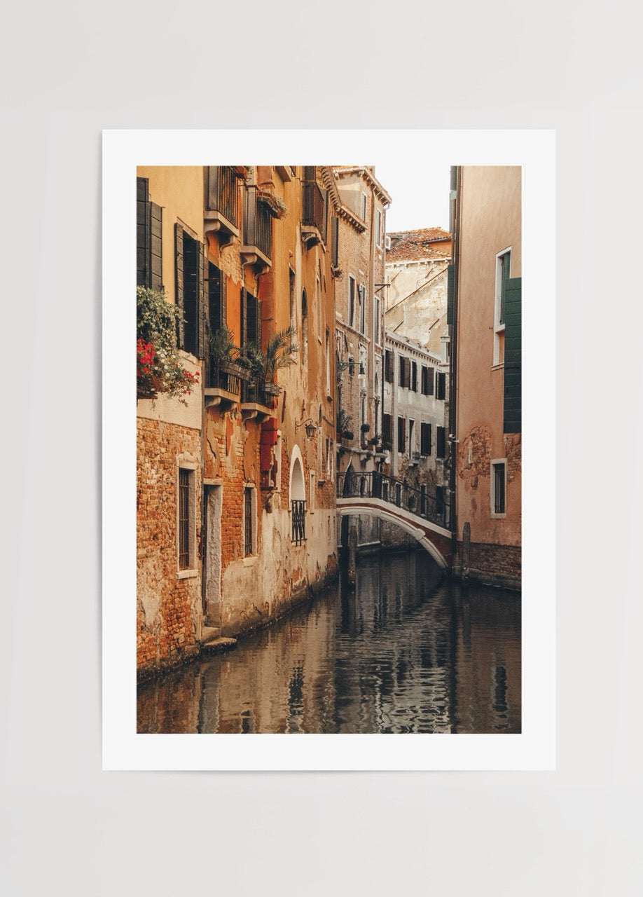 Venedik’te tarihi binalar arasında uzanan kanal ve kemerli köprü manzarası