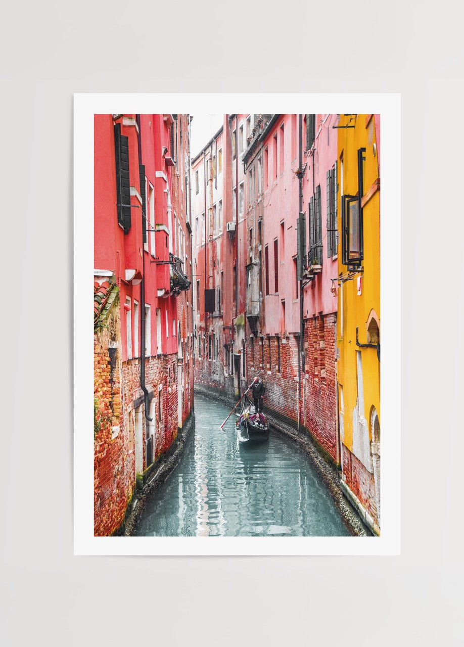 Venedik dar kanalında gondol, renkli tarihi binalar ve su yansımasıyla şehir manzarası posteri.