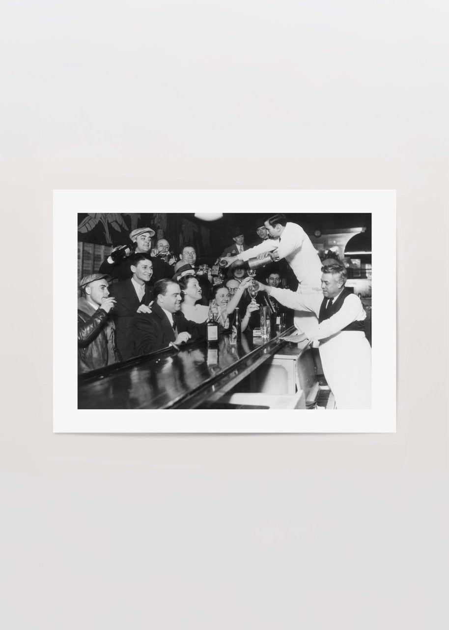Bar tezgâhında toplanmış kalabalık ve servis yapan barmenlerle çekilmiş vintage siyah beyaz fotoğraf