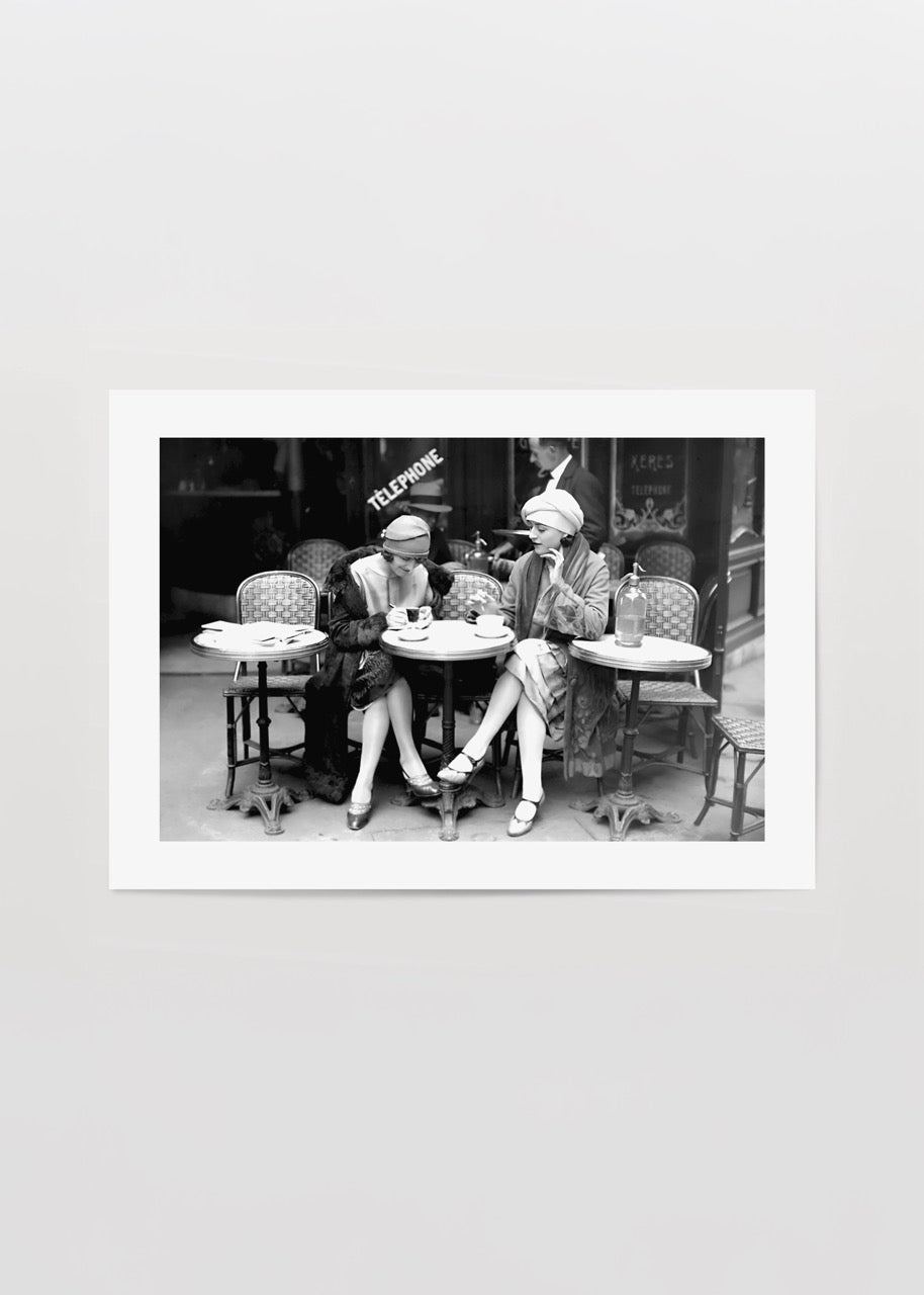 Paris sokaklarında bir kafede oturan iki kadını gösteren vintage siyah beyaz fotoğraf