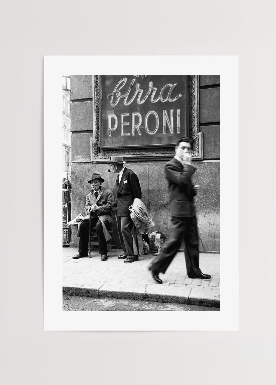 Kaldırımda bekleyen insanlar ve yürüyen figürle çekilmiş vintage siyah beyaz sokak fotoğrafı